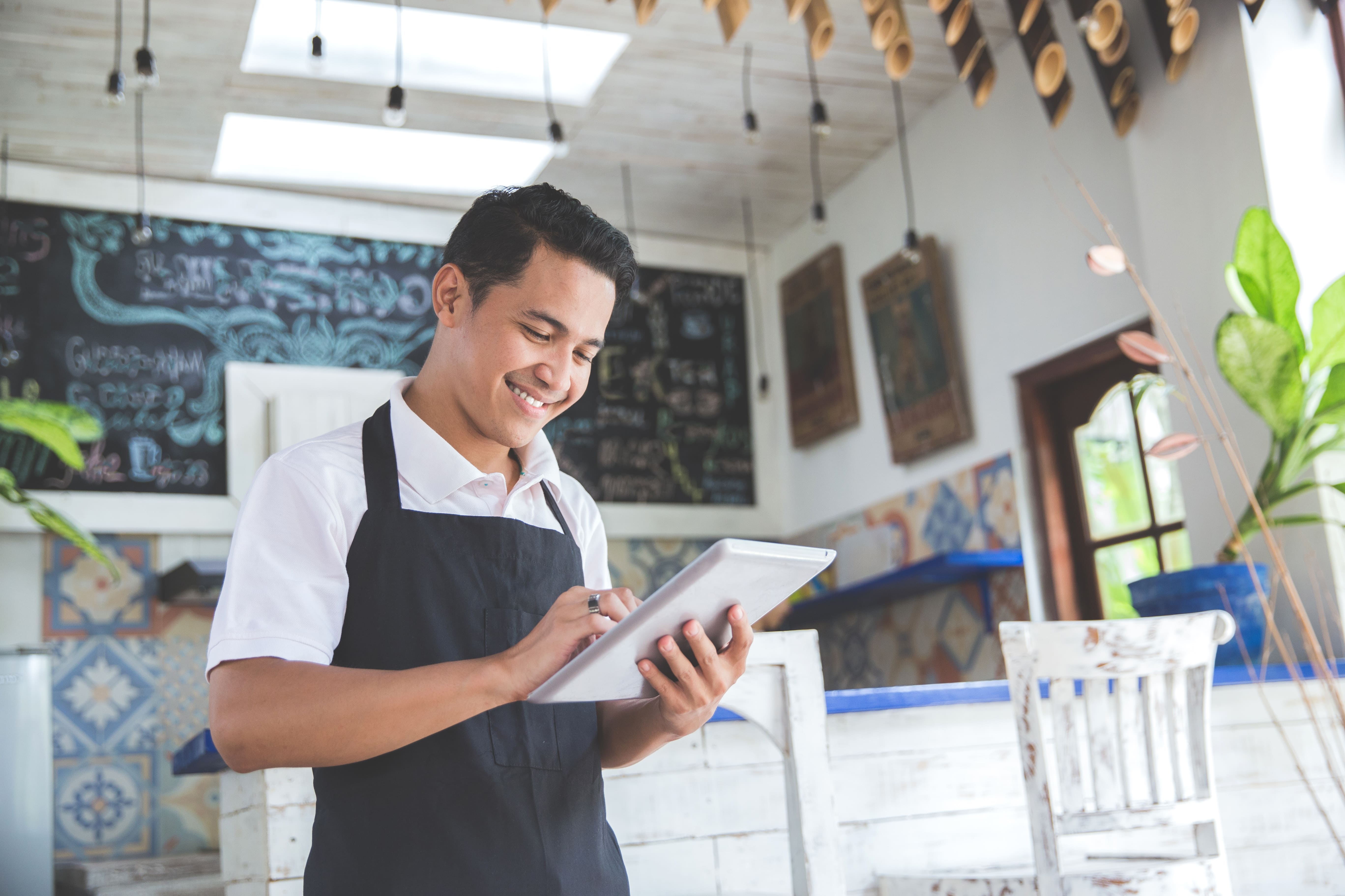 smiling shop clerk looking at his tablet